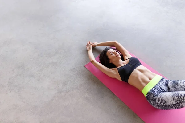 Sensual woman in sportswear on pink mat — Stock Photo, Image