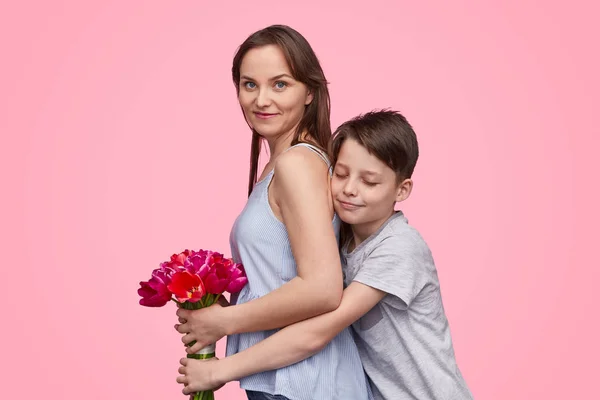 ลูกชายกอดแม่พร้อมช่อดอกไม้ — ภาพถ่ายสต็อก