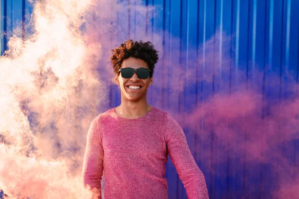 Sonriente hombre étnico en rosa humo al aire libre — Foto de Stock