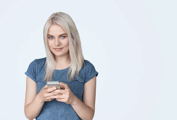 Pretty girl using phone and smiling at camera — Stock Photo, Image