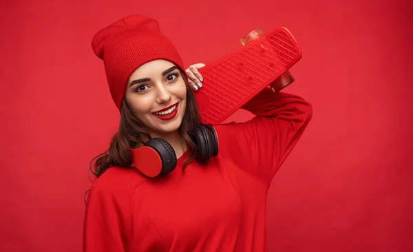 Encantadora chica hipster en ropa roja posando con longboard — Foto de Stock
