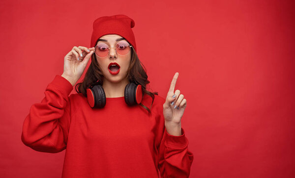 Bright woman in red outfit looking amazed holding finger up 