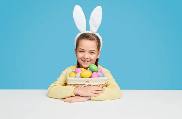 Adorable chica en orejas de conejo sentado con cesta de huevos — Foto de Stock