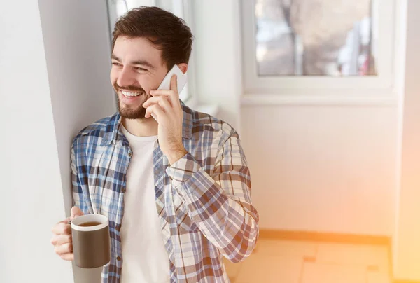 Щасливий хлопець говорить по телефону, маючи чашку кави — стокове фото