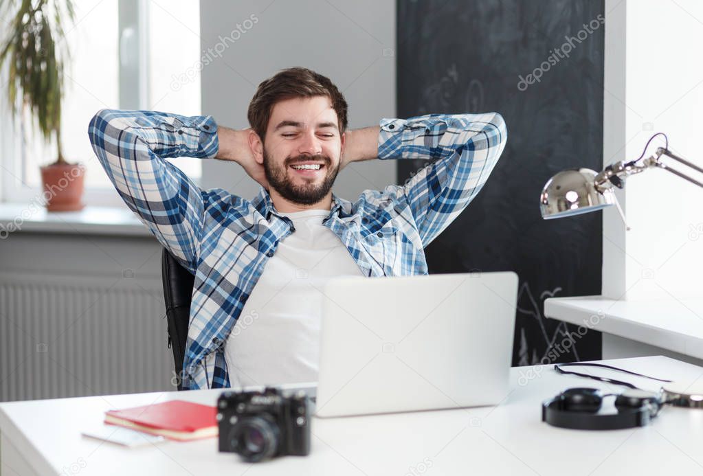 Relaxed happy man at table with laptop 