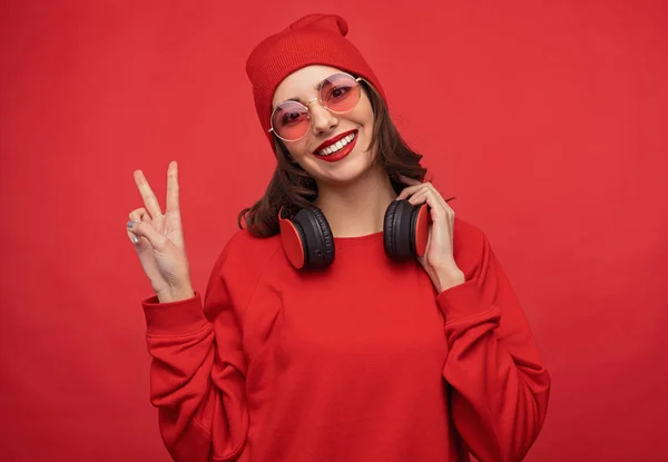 Модная девушка в красной одежде показывает два пальца — стоковое фото