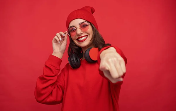 Модная яркая девушка в красной одежде указывает на камеру — стоковое фото
