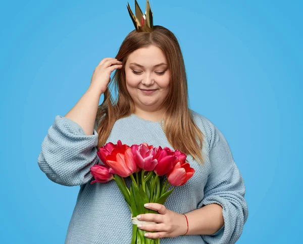 Plump woman touching hair and looking at flowers