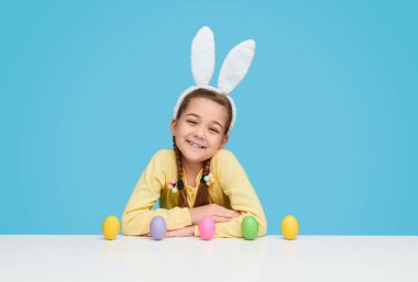 Heyecanlı kız Paskalya yumurta masada oturan kutluyor 