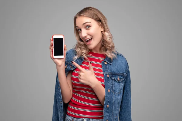 Adolescente alegre apontando para o smartphone — Fotografia de Stock