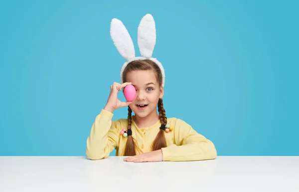 Linda niña que cubre el ojo con huevo de Pascua — Foto de Stock