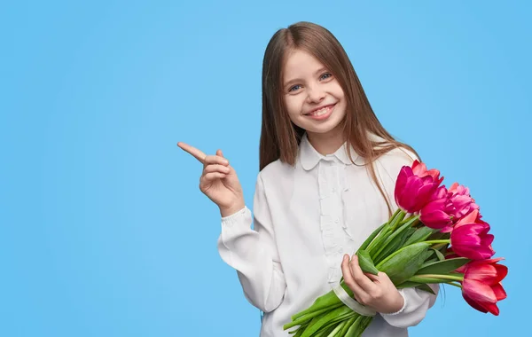 Hravá dívka s jarní květiny ukazující daleko — Stock fotografie