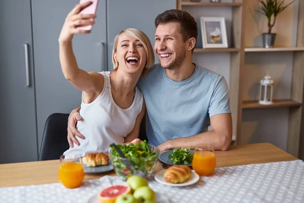 Laughing couple taking selfie during breakfast — Stock Photo, Image