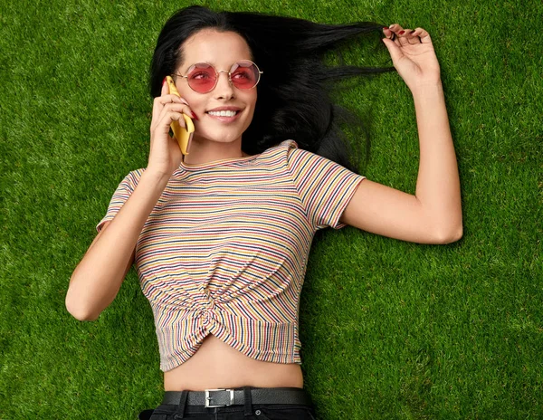 Mujer hablando por teléfono y tocando el pelo en el césped — Foto de Stock