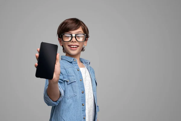 Menino em óculos mostrando smartphone — Fotografia de Stock