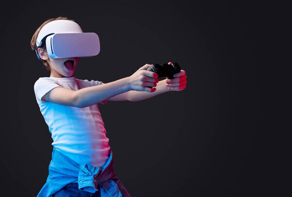 Amazed kid in VR headset playing videogame