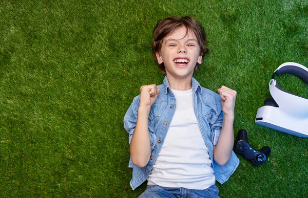 Niño con auriculares Vr en el prado celebrando victoria —  Fotos de Stock