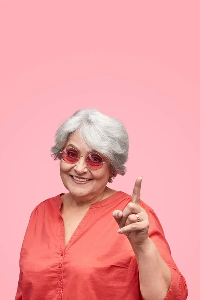 Leende senior kvinna som pekar uppåt — Stockfoto