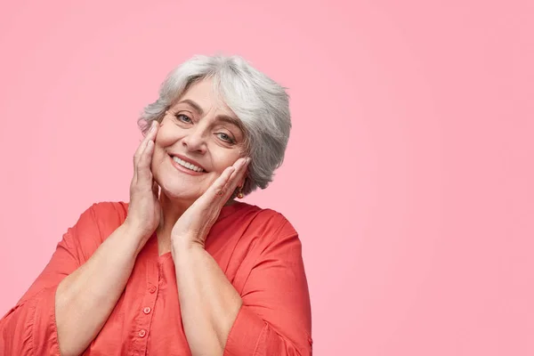 Sonriente mujer mayor tocando la piel — Foto de Stock