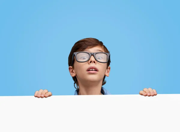 Curious kid looking from behind board — Stock Photo, Image