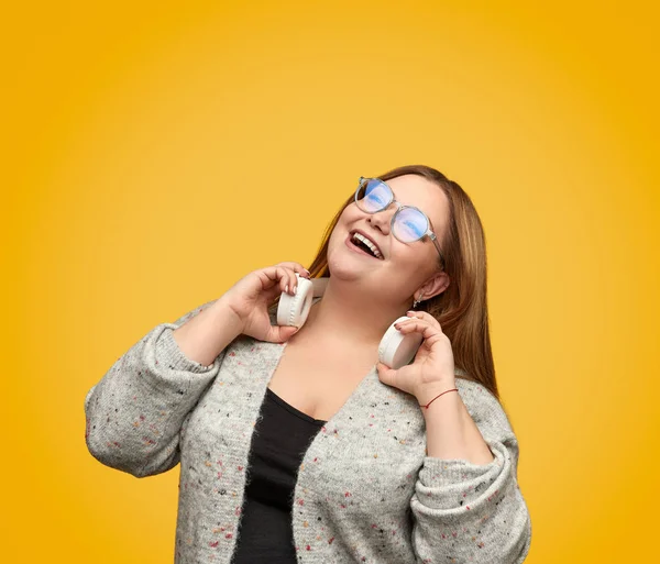 Cheerful plump woman with headphones looking up — Stock Photo, Image