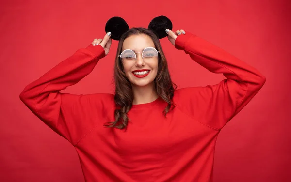 Улыбающаяся женщина в красной одежде с мышиными ушами — стоковое фото