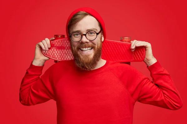 Alegre hipster con monopatín mirando a la cámara — Foto de Stock