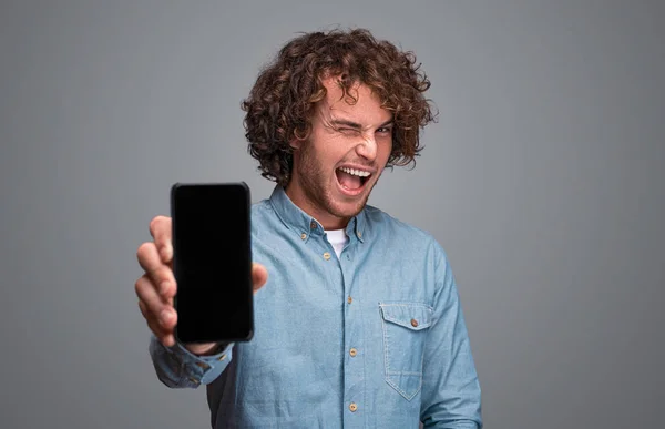 Homem piscando e demonstrando smartphone — Fotografia de Stock