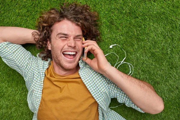 웃는 사람이 잔디밭에 스마트폰에 말하기 — 스톡 사진