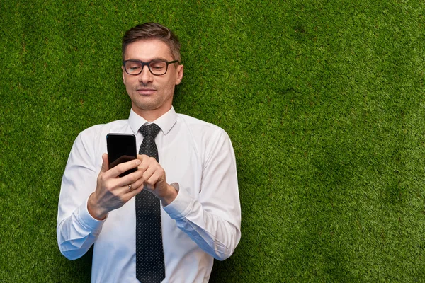 Biznesmen korzystanie ze smartfona na trawnik — Zdjęcie stockowe