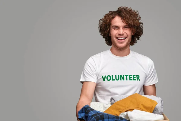Cheerful volunteer with clothes — Stock Photo, Image