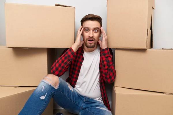 Chico sorprendido cerca de cajas de cartón — Foto de Stock