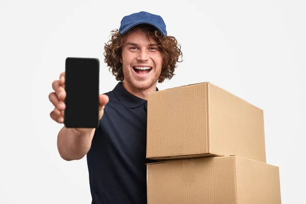 Mensajero alegre con cajas que muestran el teléfono inteligente — Foto de Stock