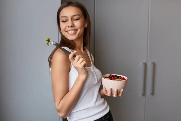 Chica coqueta de pie con un tazón de ensalada de frutas — Foto de Stock