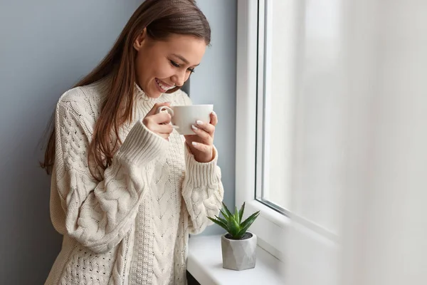 Fröhliche Frau trinkt Tee am Fenster — Stockfoto