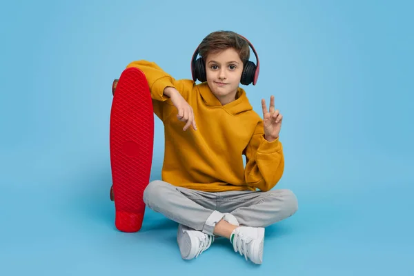 Cool pojke med skateboard göra en gest V tecken — Stockfoto