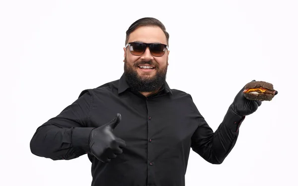 Overweight man showing burger and gesturing thumb up — Stock Photo, Image