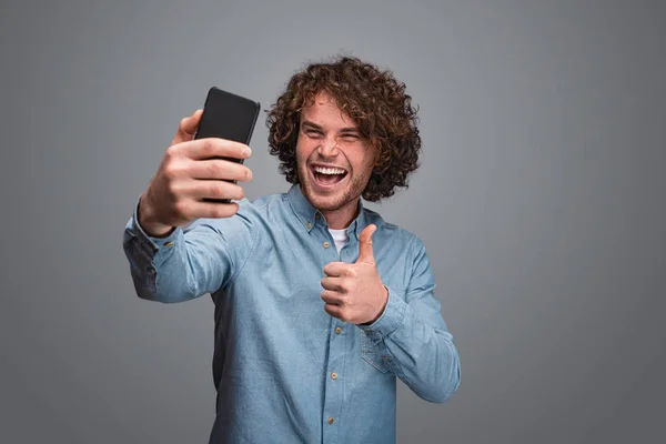 Hombre excitado señalando el pulgar hacia arriba y tomando selfie —  Fotos de Stock