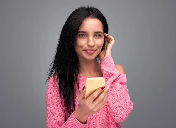 Mulher encantadora com smartphone tocando o cabelo — Fotografia de Stock