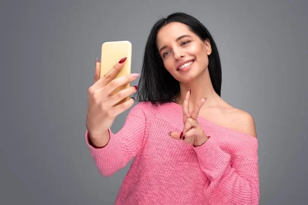 Mujer joven mostrando V signo y tomando selfie — Foto de Stock