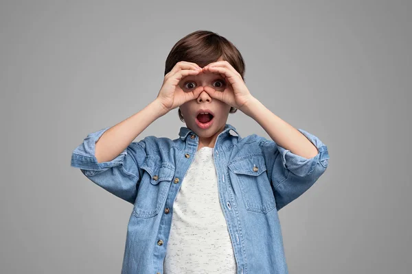 Shocked boy looking at camera through hand binoculars — Stock Photo, Image