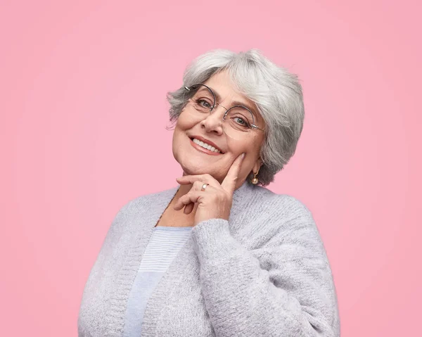 Улыбающаяся пожилая женщина касается щеки — стоковое фото