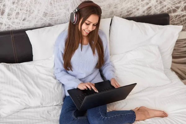 Gadis impian mendengarkan musik dengan laptop di tempat tidur — Stok Foto