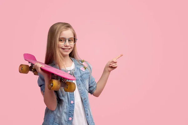 Fröhliches Kind mit Skateboard, das auf leeren Raum zeigt — Stockfoto