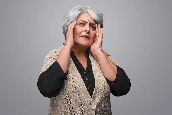 Elderly woman with migraine looking away