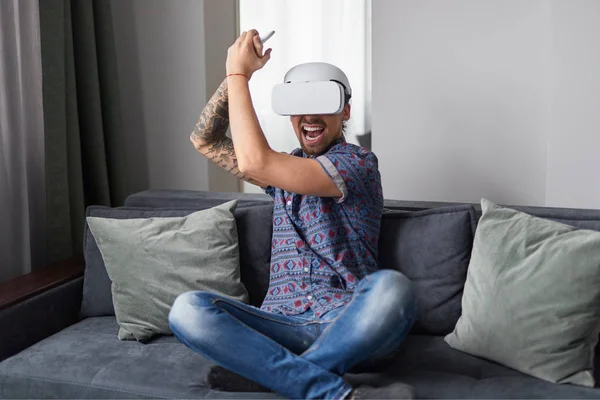 Excited guy playing action VR game at home