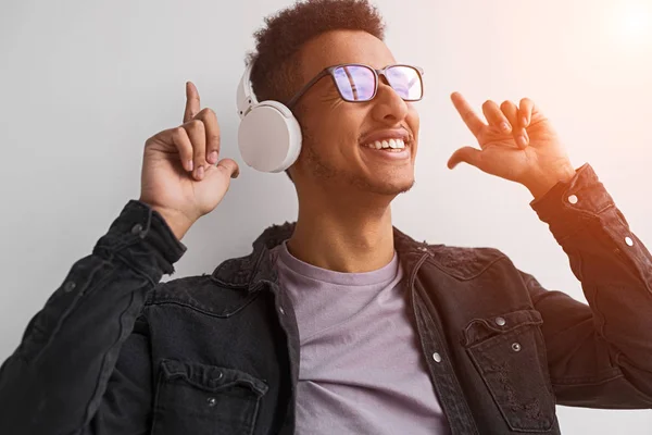 Cheerful black guy listening to music and pointing up — Stock Photo, Image