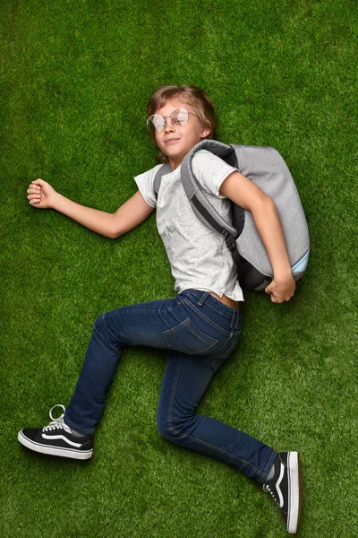 Школьник бежит по зеленой лужайке — стоковое фото