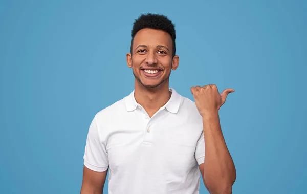 Cheerful ethnic guy pointing aside — Stock Photo, Image