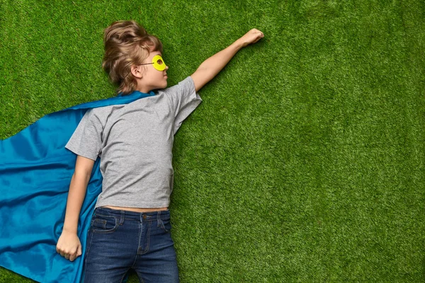 Супергерой в героїчній позі лежить на газоні — стокове фото